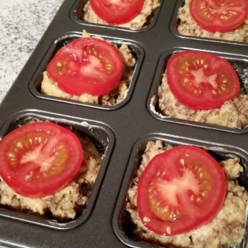 Die Tomaten in dicke Scheiben schneiden und die Küchlein damit belegen.
