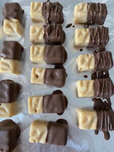 und halb oder ganz in Schokolade tunken. Auf Alufolie geben und kurz fest werden lassen.